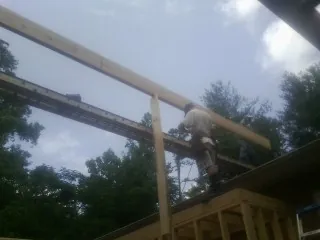 Carpenter setting a ridge beam over a new addition frame — Ice Dam Removal by Roofing Brothers in Cazenovia