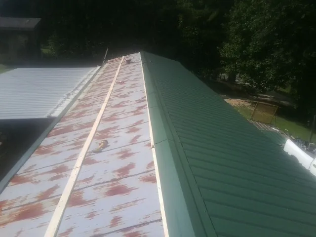 Old rusted panels beside newly installed green metal roofing — Wind Damage Roof Repair by Roofing Brothers in Cazenovia