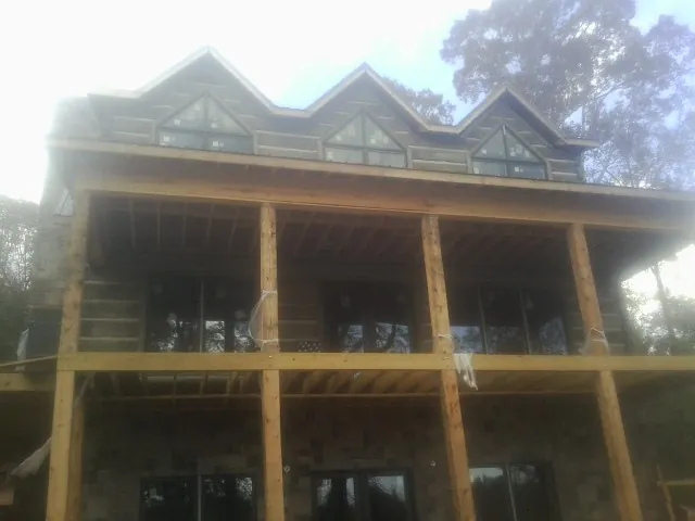 Dormers and porch framing on a large log home under construction — Roof Coating work by our crew in Cazenovia