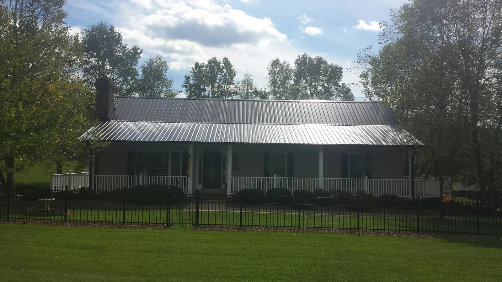 Gray metal roof on a brick ranch with a full width front porch — Gutter Guard Installation work by our crew in Cazenovia