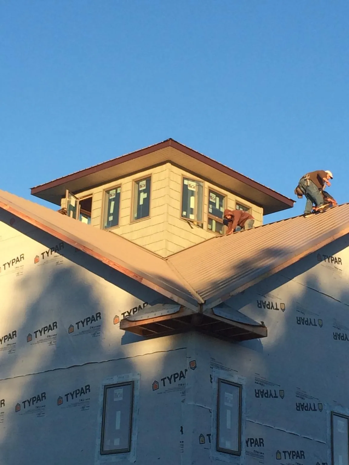Roofers working around a rooftop cupola on a new metal roof at sunset — Roof Waterproofing in Cazenovia by Roofing Brothers